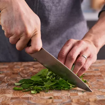 chef's knife chopping herbs on wooden block